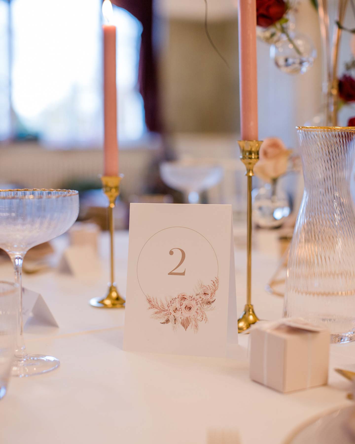 Tischnummer mit rosa Blüten-Illustrationen steht auf der Hochzeitstafel.