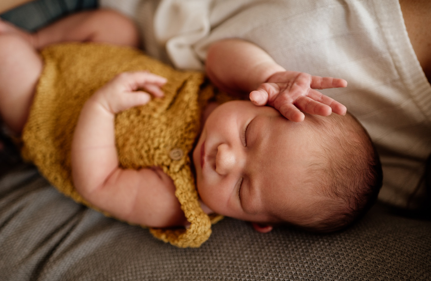 schlafendes Baby in senfgelbem, ärmellosen Strickanzug