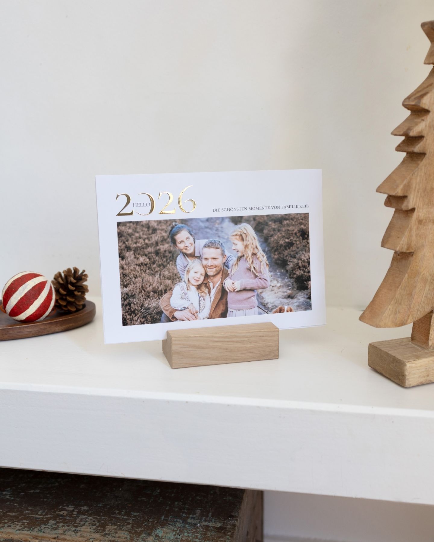 Fotokalender mit Foto von verliebten Pärchen steht auf einem Holztisch und ein Nussknacker steht daneben. 