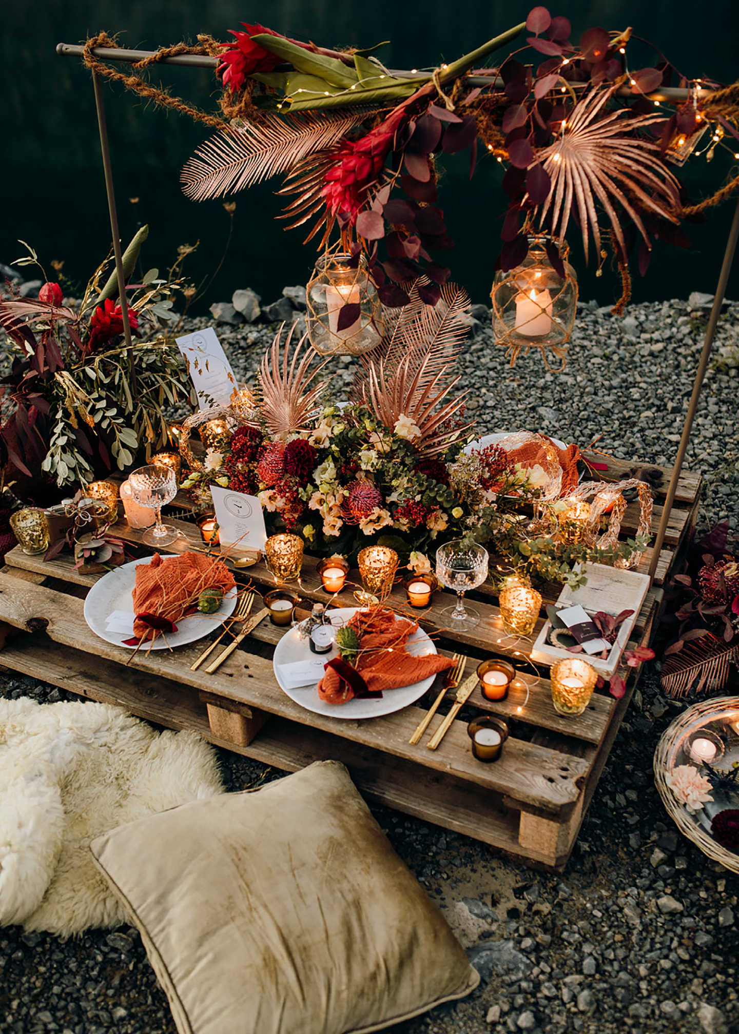 Die Hochzeitstafel aus einer Holzpalette, mit warmen Farbakzenten geschmückt vor dem Wasser im Steinbruch
