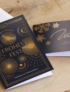 Geschäftliche Weihnachtskarten mit Folienveredelung  und Kuverts auf einem Tisch.