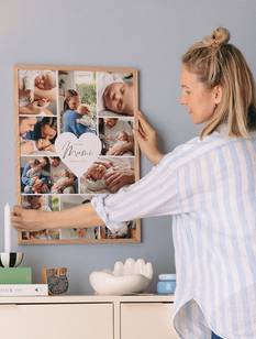Junge Mutter hängt ihr Muttertagsgeschenk, eine gerahmte Cllage, an die Wand