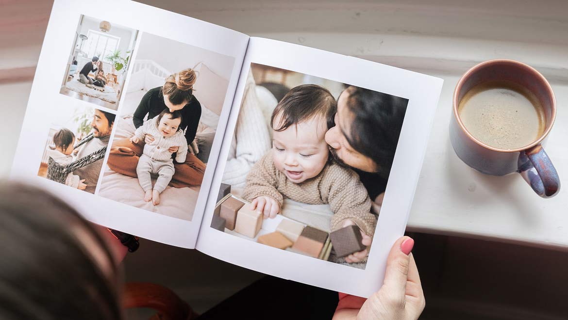 Frau schaut sich emotionales Fotobuch bei einer Tasse Kaffee an.