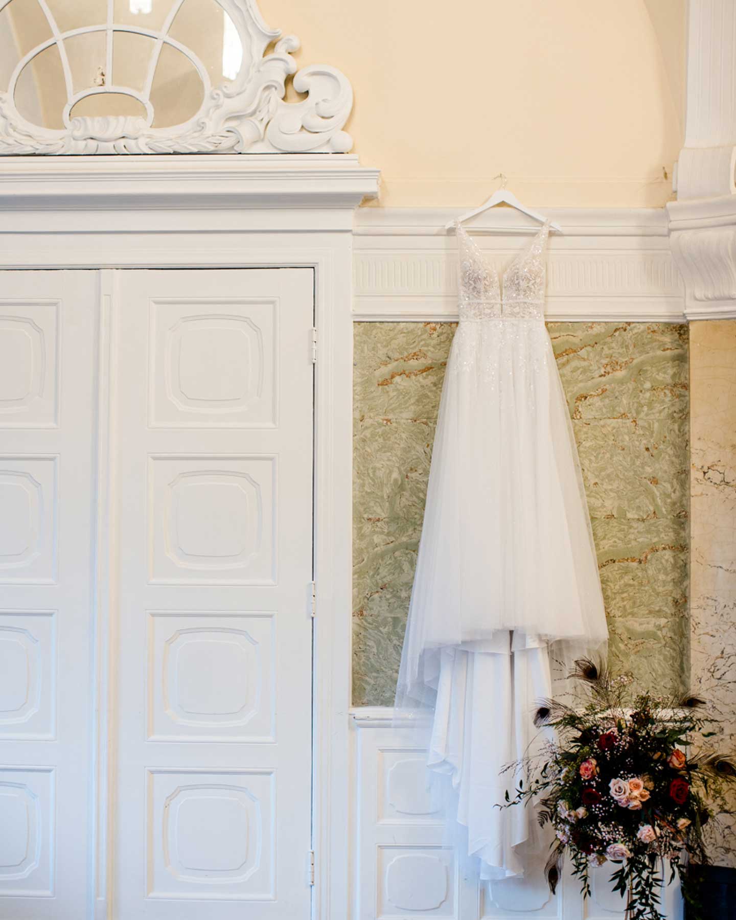 Romantisches Brautkleid hängt an Bügel an der Wand für das Getting Ready der Braut.