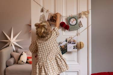 kleines Mädchen vor Zimmertr, die mit Weihnachtskarten dekoriert ist