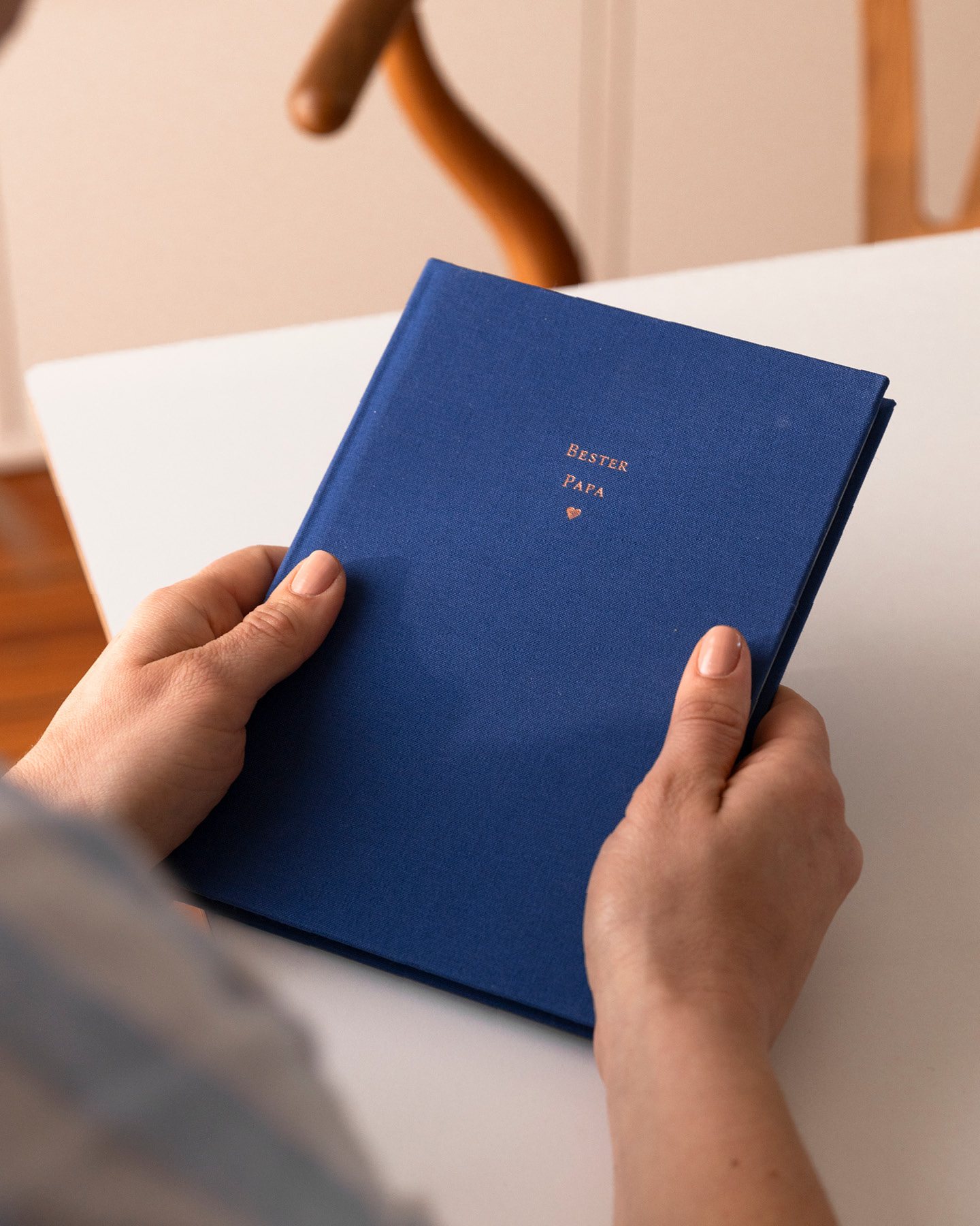 Bildausschnitt: Junge Mitter mit ihremMuttertagsgeschenk im Arm, einem personalisierten Notizbuch