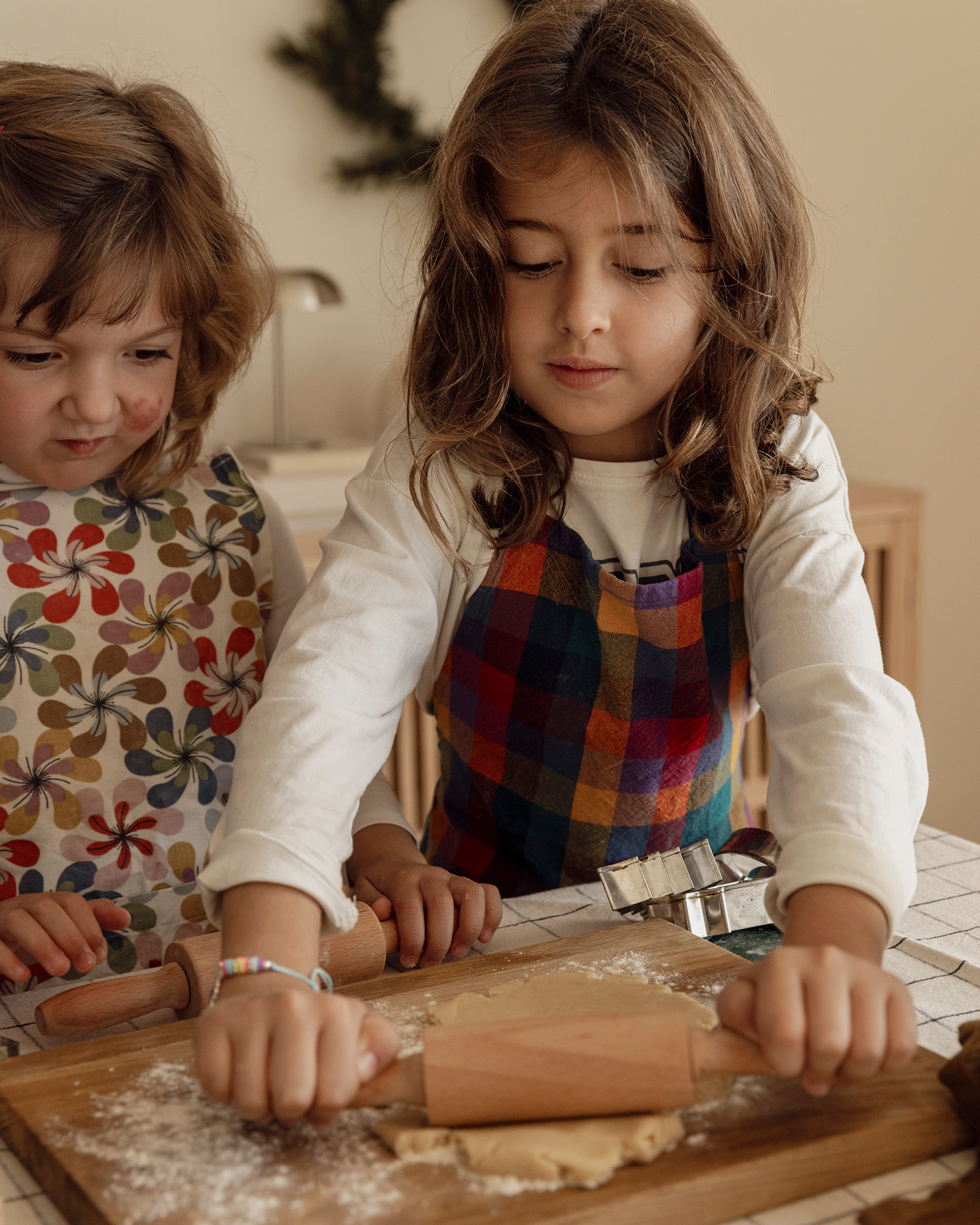 Zwei kleine Mädchen beim Ausrollen von Weihnachtsplätzchenteig