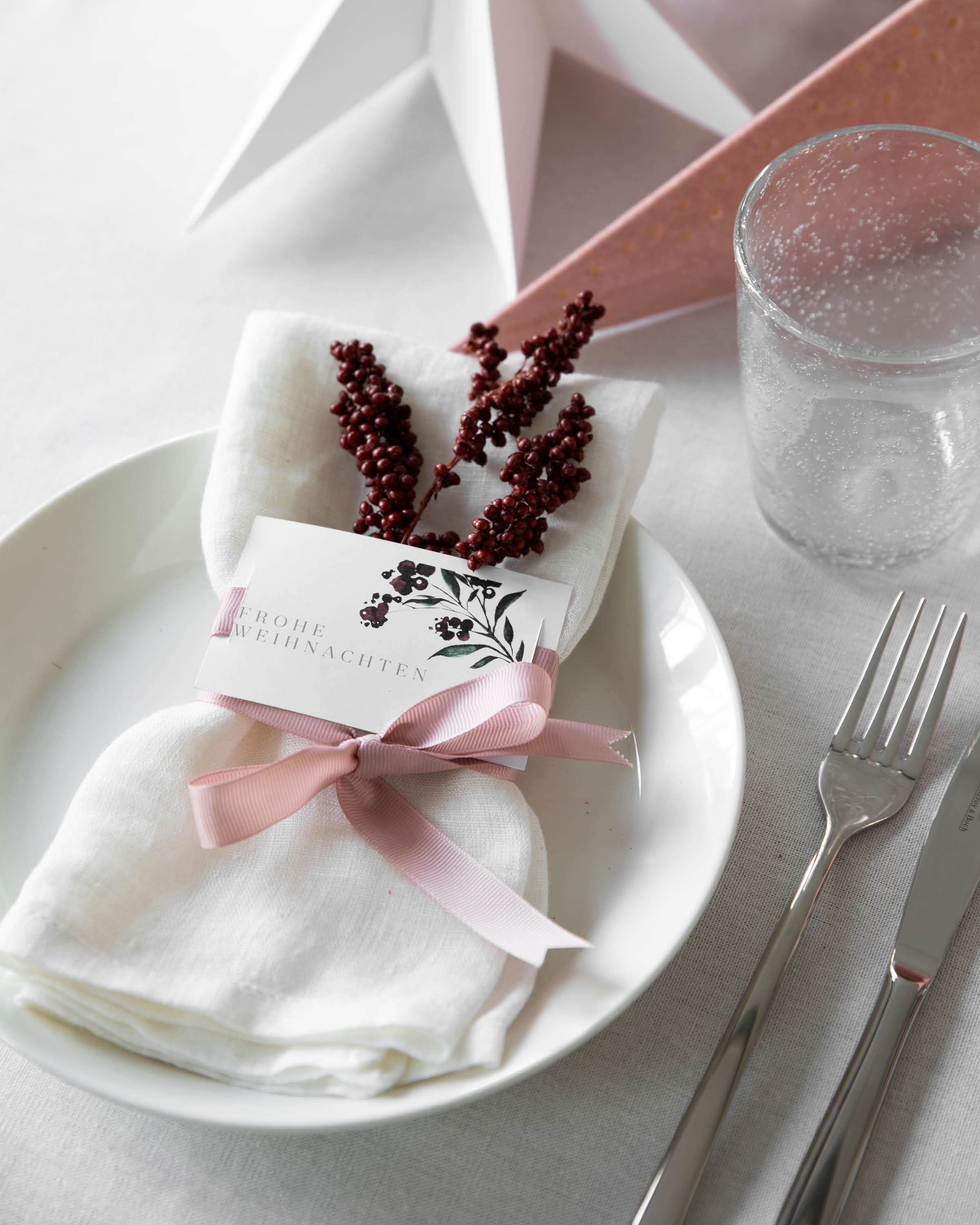 Weiße Stoffserviette verziert mit roten Beeren, eine rosa farbigen Schleife und Menükarten im schlichten Beerendesign. So einfach Tischdekoration selber machen.