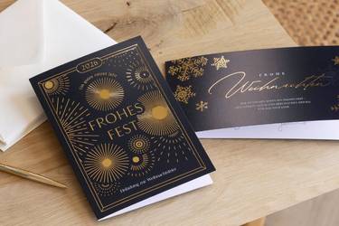 Geschäftliche Weihnachtskarten mit Folienveredelung  und Kuverts auf einem Tisch.