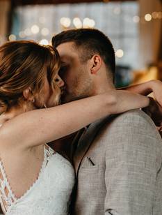 Hochzeitspaar küsst sich in der liebevoll dekorierten Hochzeitsscheune
