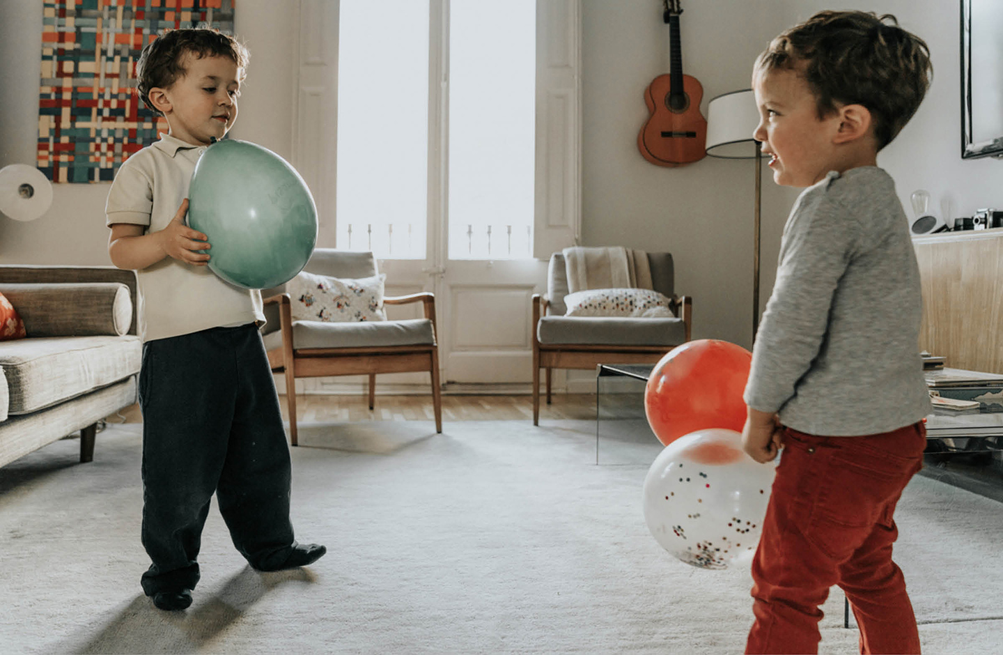 Zwei kleine Jungs spielen im Wohnzimmer mit Luftballons
