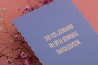 Violette Beileidskarte mit kleinen Blüten dekoriert auf rosa Hintergrund