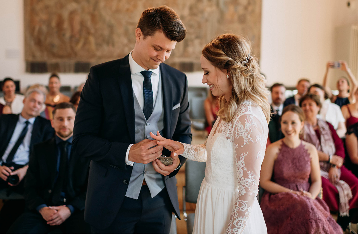 Bräutigam steckt seiner Braut nach der Eheschließung den Ring an den Finger.