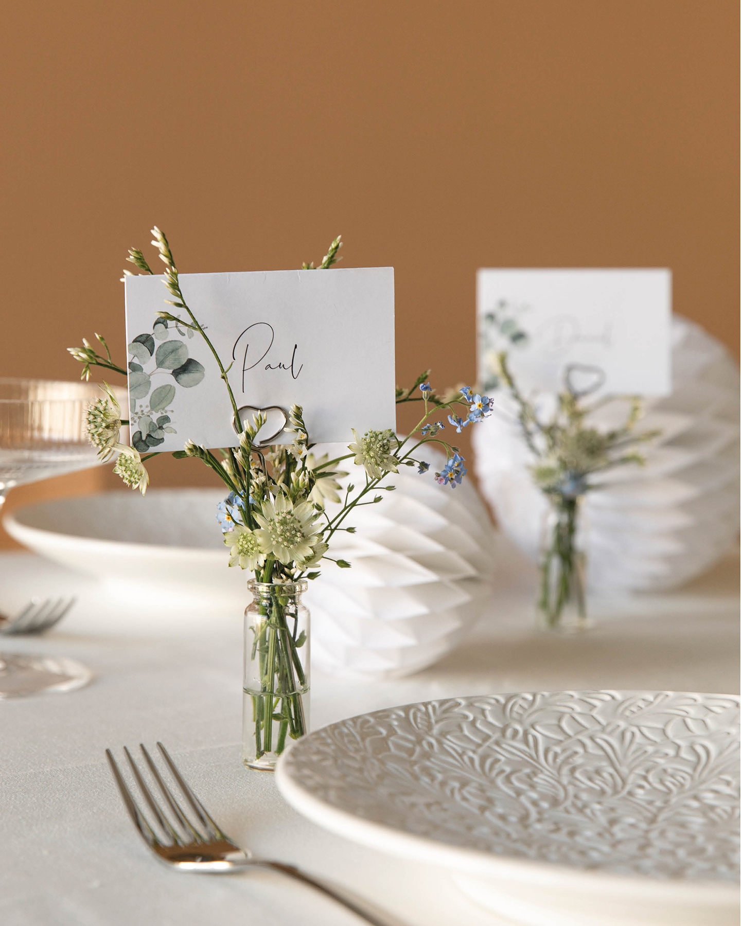 Tischkarten zur Hochzeit dekoriert in kleinen Fläschchen gefüllt mit Blümchen dekoriert auf der Hochzeitstafel.