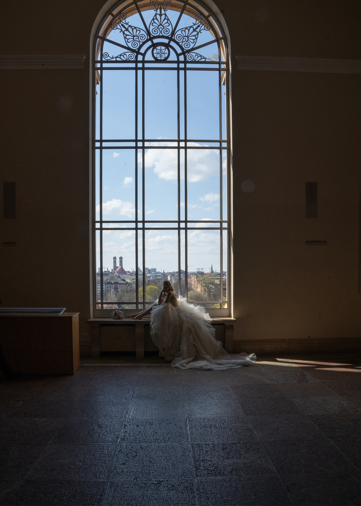 Die Braut posiert in der atemberaubenden Location vor einem riesigen, mit vielen Details versehenen Fenster.