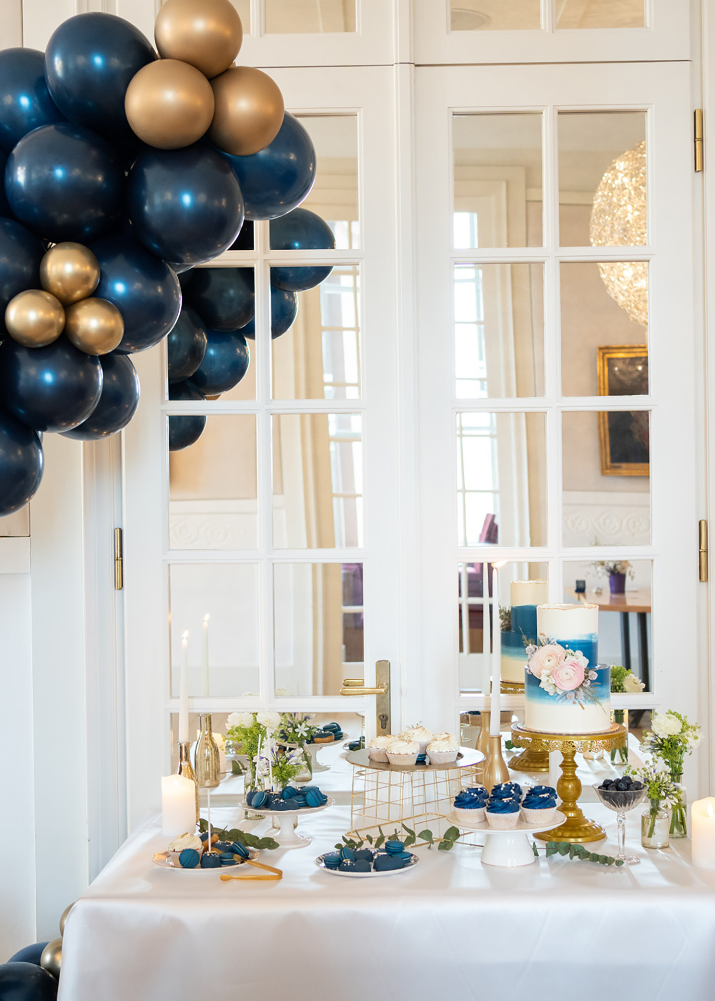 Die Hochzeitslocation von innen wurde dezent geschmückt, mit blauen Ballons und goldenen Elementen. Der Tisch, auf dem Ein Buffet aus der Hochzeitstorte und weiteren süßen Gebäckspeisen, besteht, ist auf einem extra Tisch angerichtet.
