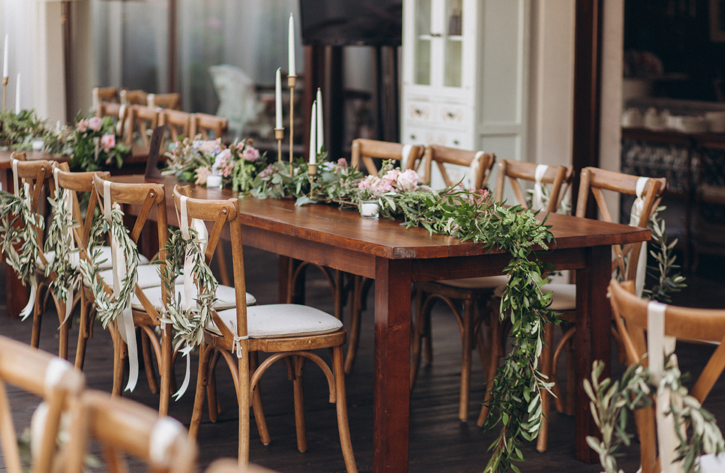 Holztisch ist minimalistisch zur Hochzeit mit grünen Zweigen und rosa Pfingstrosen dekoriert.