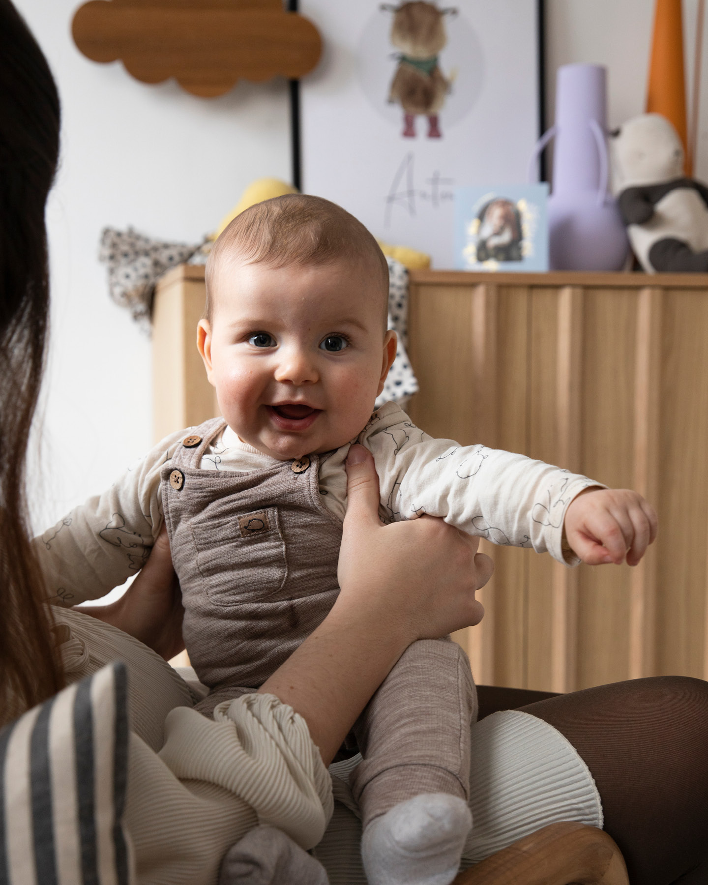 Mutter (nicht im Bild) hält ihr lächelndes Baby auf dem Schoß