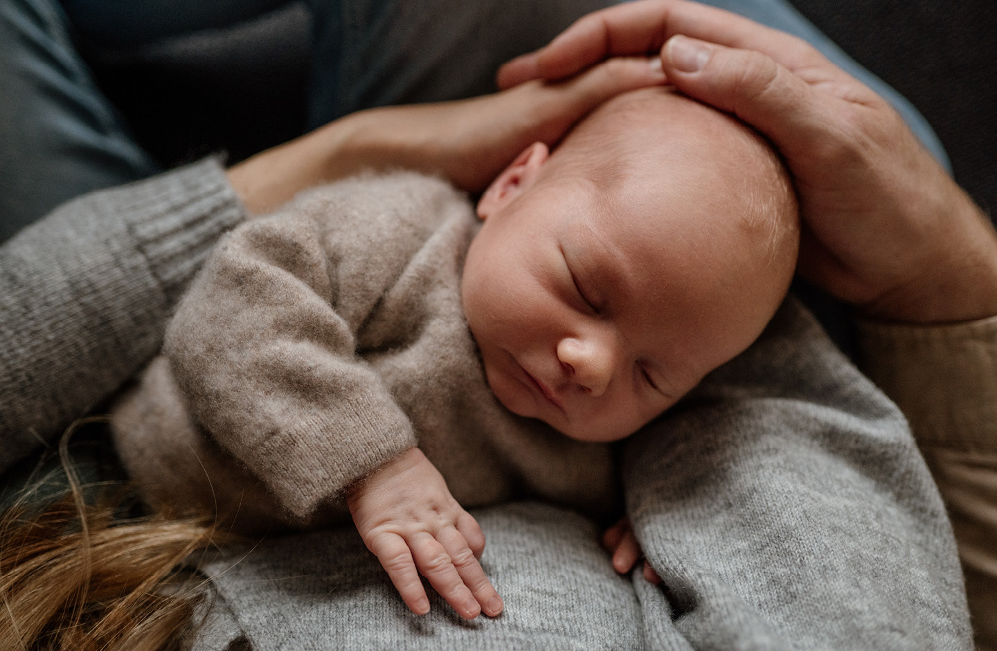 Schlafendes Baby im Arm des Vaters im Wochenbett