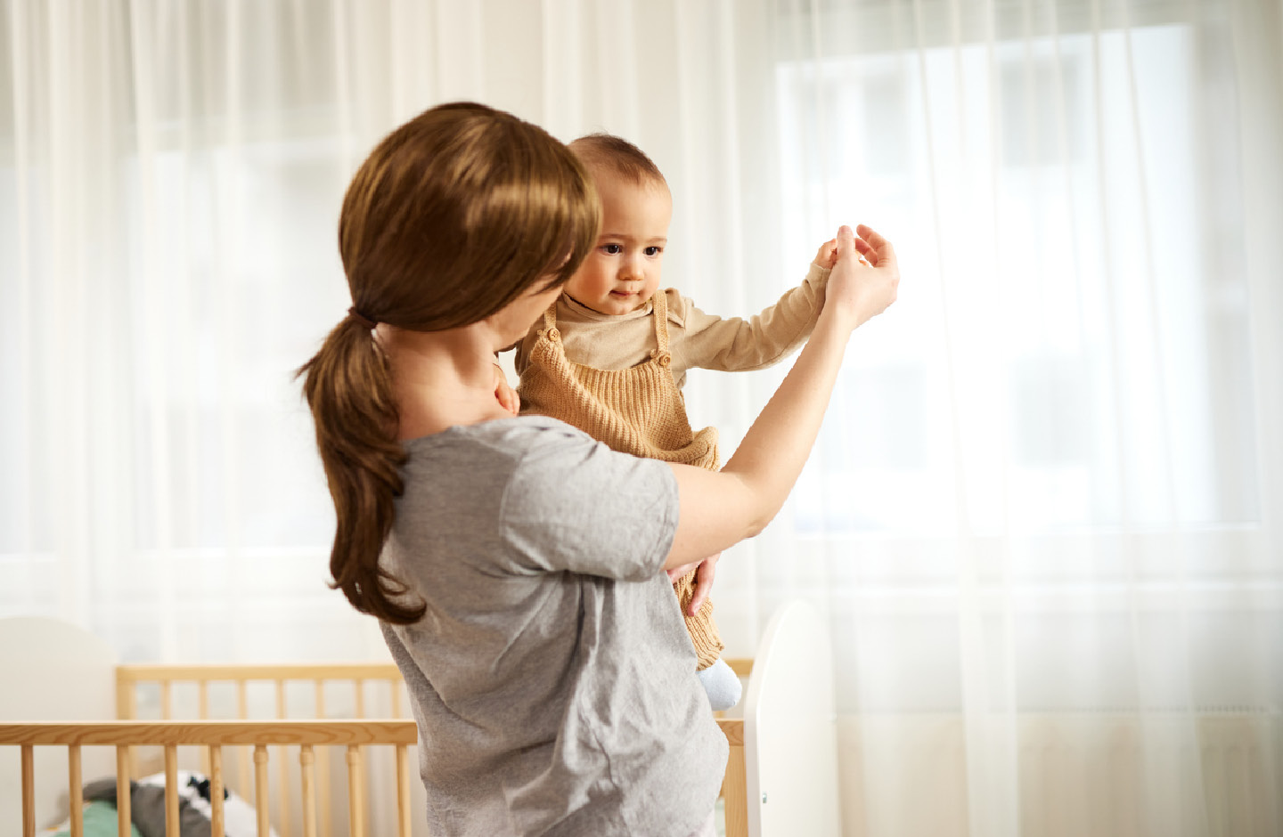 Mutter tanzt mit ihrem Baby auf dem Arm durchs Babyzimmer