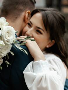 Hochzeitspaar umarmt sich mit Brautstrauß in der Hand