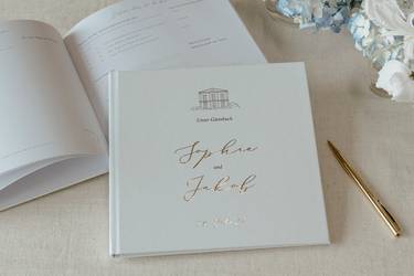 Hochzeitsgästebuch und goldfarbener Kugelschreiber auf einem Tisch