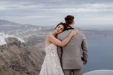 Hochzeitspaar in zärtlicher Pose vor Kulisse von Santorini