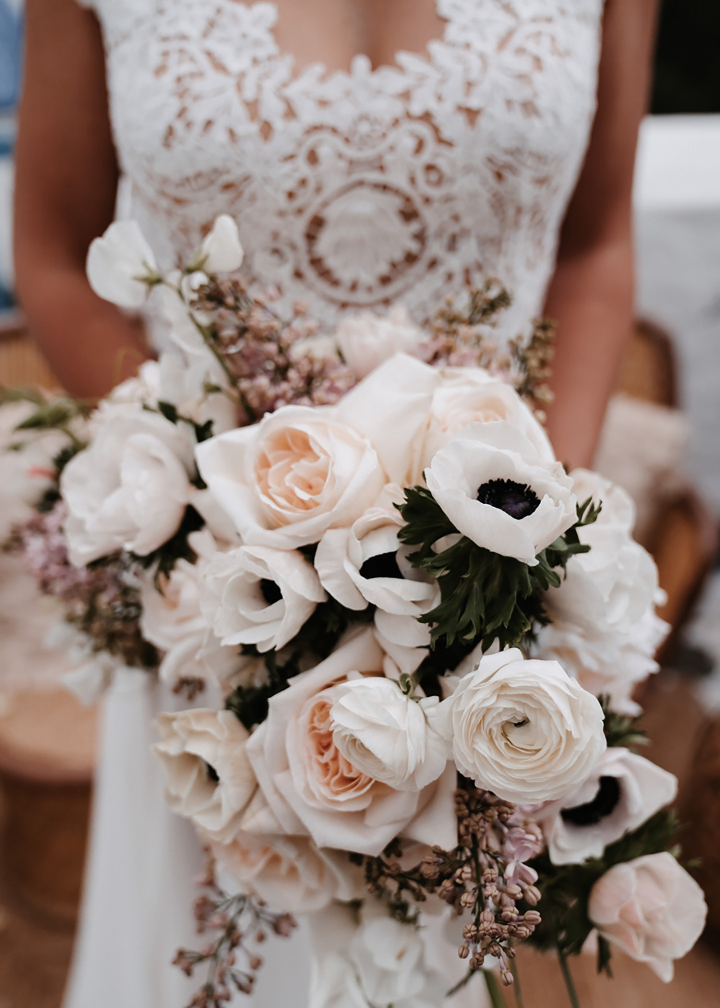 Der Brautstrauß in hellen Orange, Peach, Rosa und Pudertönen wird von der Braut vor ihrem Kleid gehalten. 