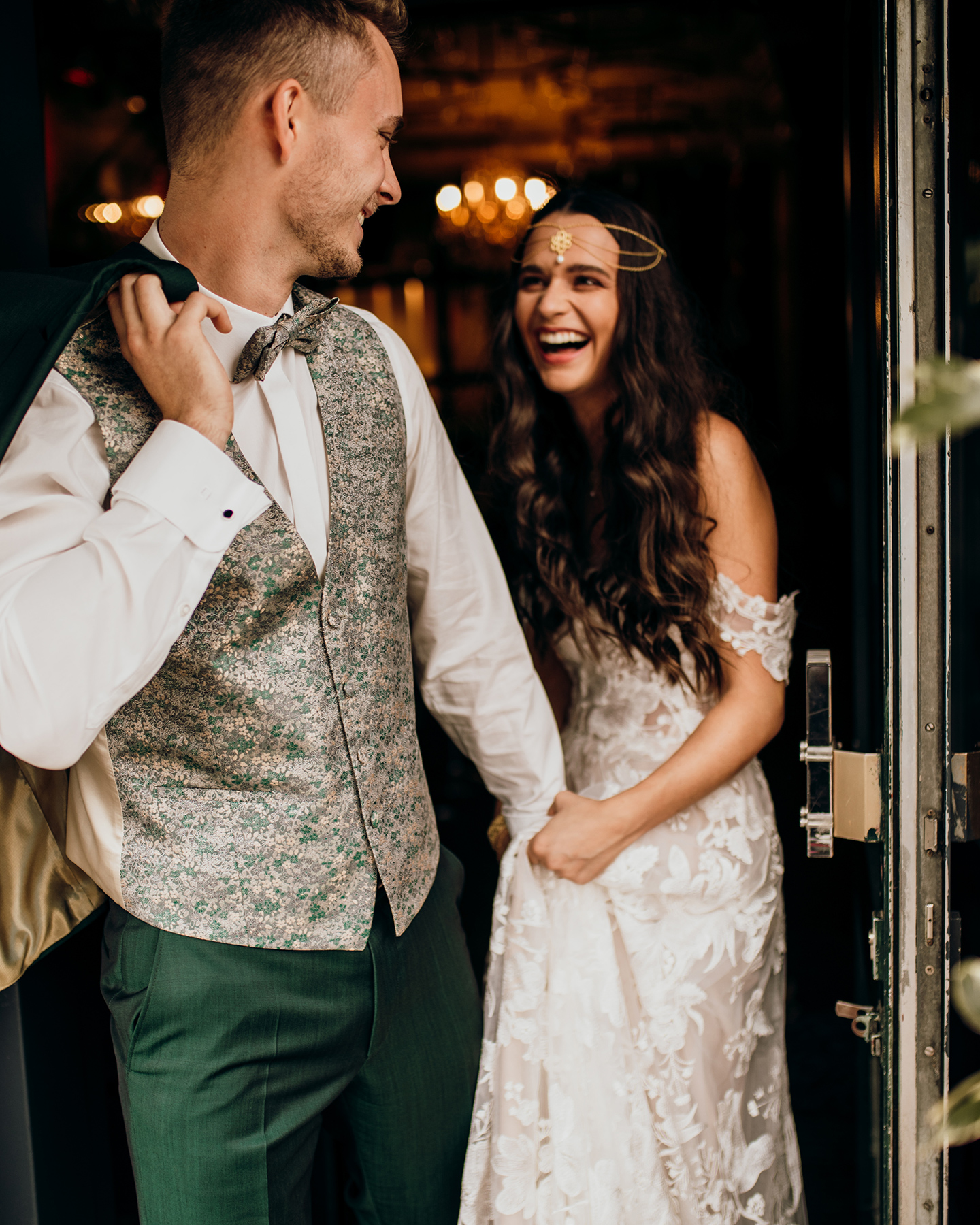 Das Brautpaar tritt lachend aus der Tür hinaus ins Freie. 
